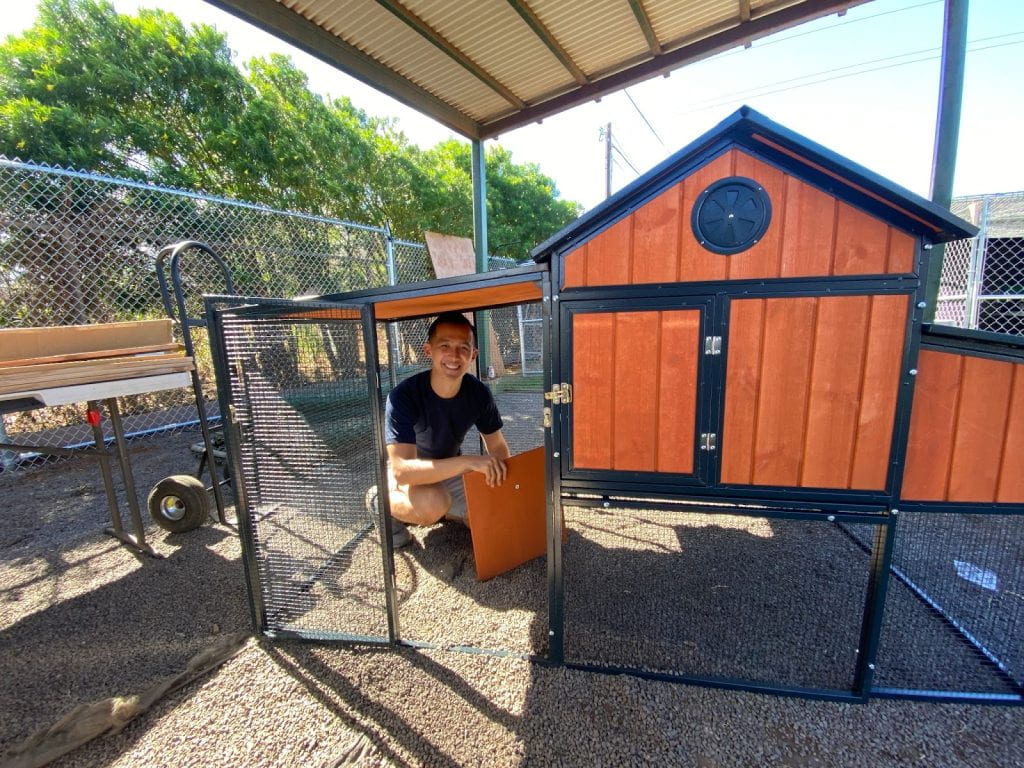 Dr. Wesley Cheung poses with a makeshift chicken coop turned into a cat enclosure.